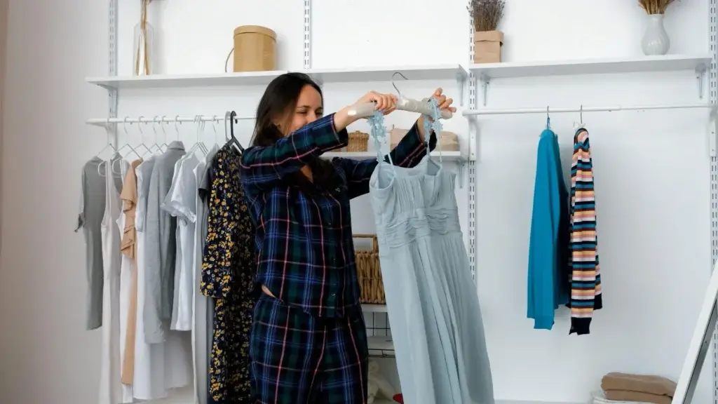 Woman selecting a versatile clothing piece from a capsule wardrobe while evaluating wardrobe gaps and planning thoughtful purchases.