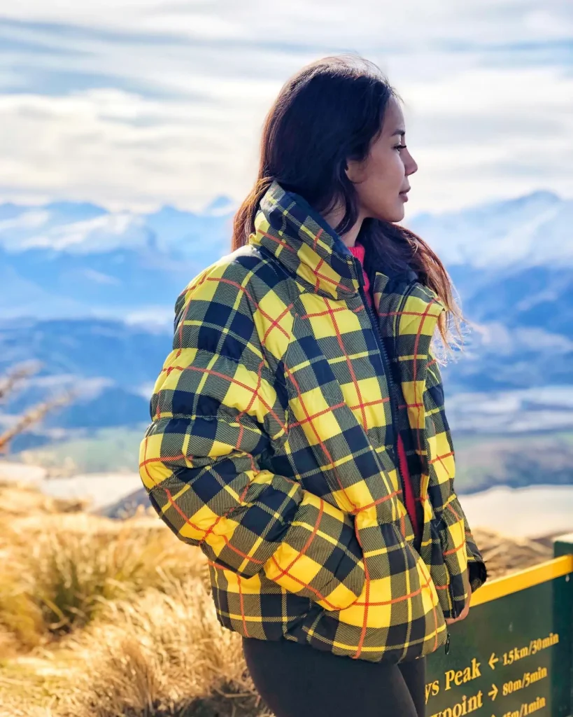 Woman wearing a plaid puffer jacket during a cold-weather mountain trip