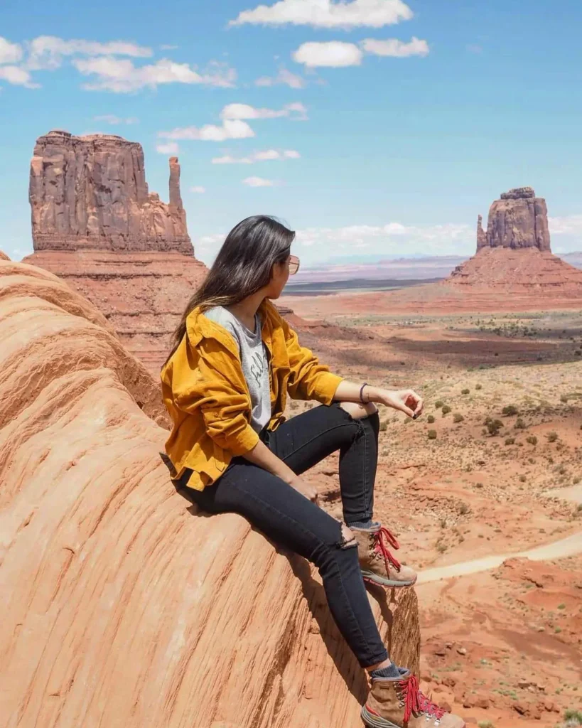Woman wearing a mustard jacket, black jeans, and hiking boots in a desert landscape