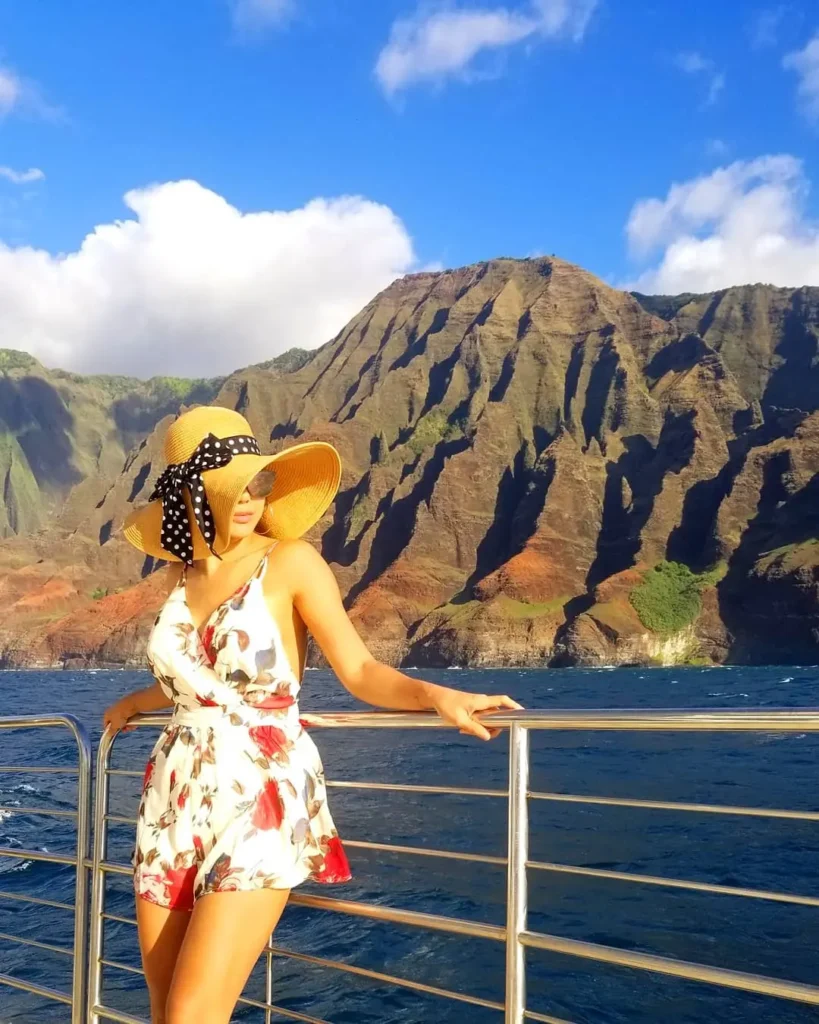 Woman wearing a floral romper and wide-brim sun hat on a coastal vacation