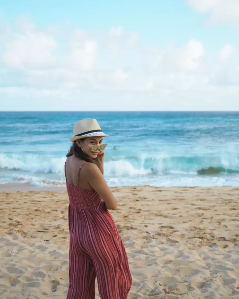 Woman wearing a red striped jumpsuit and sun hat on the beach