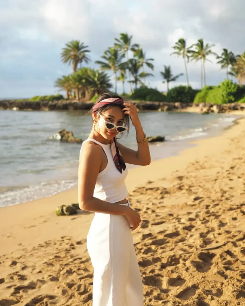 Woman wearing a white summer outfit with sunglasses on a tropical beach