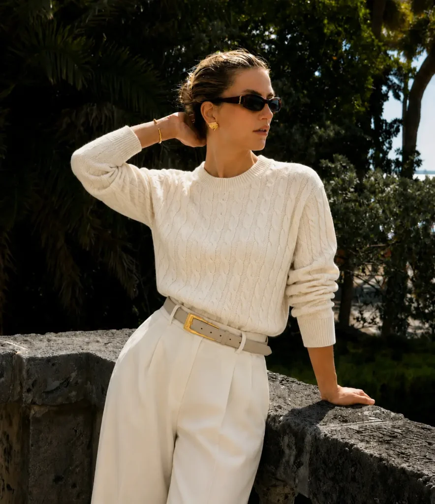Woman wearing an ivory cable-knit wool sweater with cream wide-leg trousers in an elegant old money outfit.
